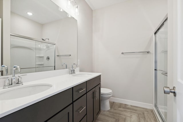 bathroom with vanity, parquet flooring, a shower with shower door, and toilet