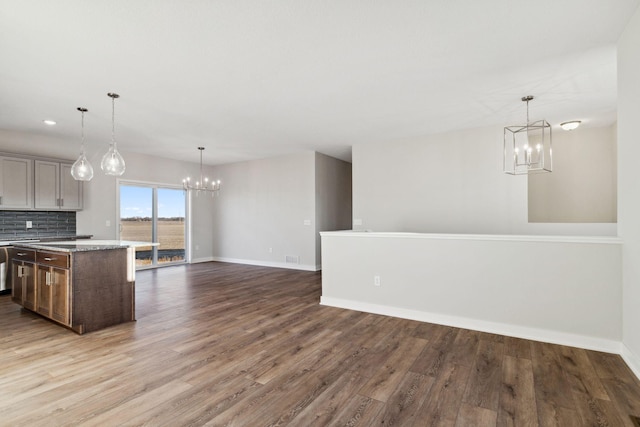 kitchen featuring a kitchen island, backsplash, an inviting chandelier, and decorative light fixtures