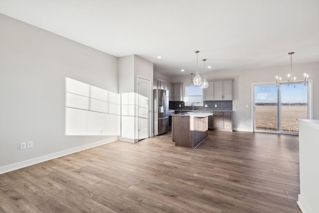 kitchen with pendant lighting, stainless steel fridge with ice dispenser, hardwood / wood-style floors, and a kitchen island