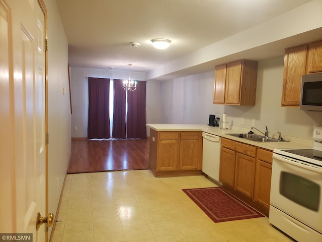 kitchen featuring kitchen peninsula, white appliances, sink, decorative light fixtures, and an inviting chandelier