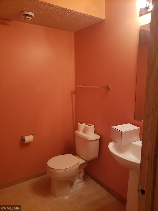 bathroom with tile patterned floors, toilet, and a textured ceiling