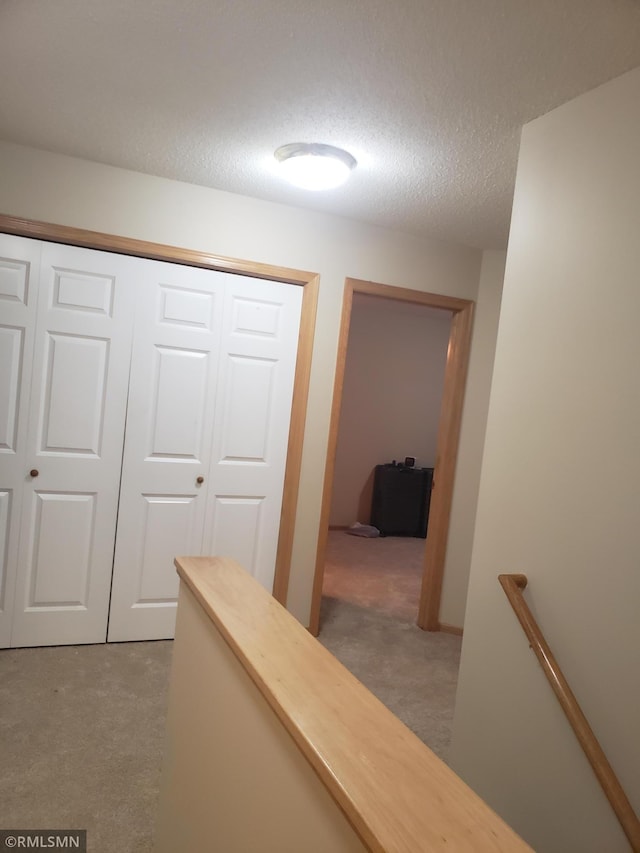 hallway with a textured ceiling and dark carpet