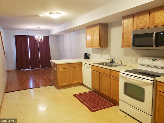 kitchen with white appliances, sink, hanging light fixtures, kitchen peninsula, and a chandelier