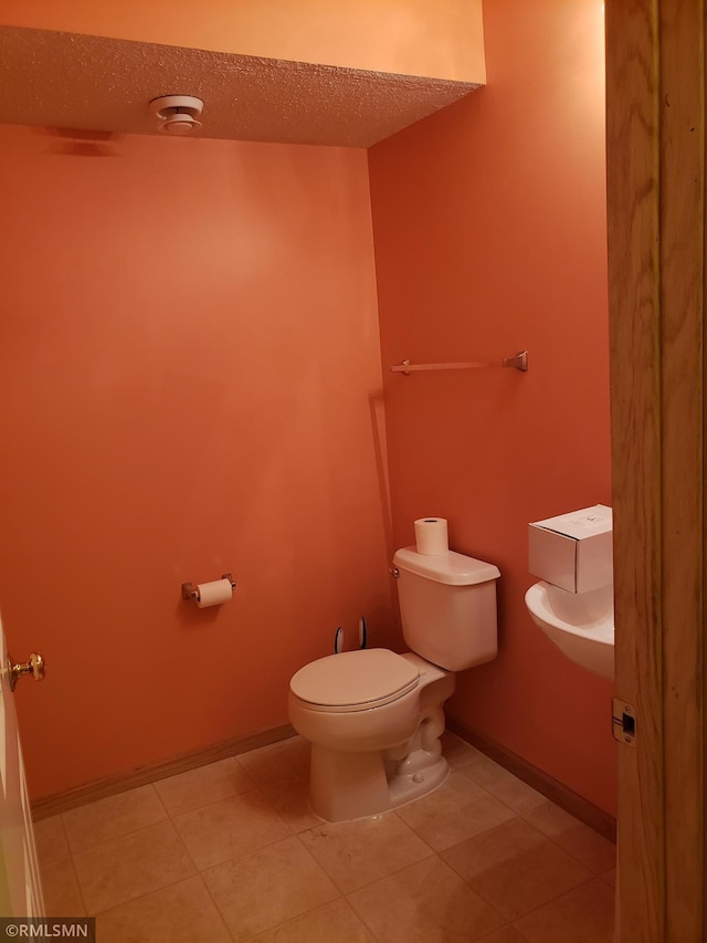 bathroom featuring tile patterned floors, toilet, and a textured ceiling