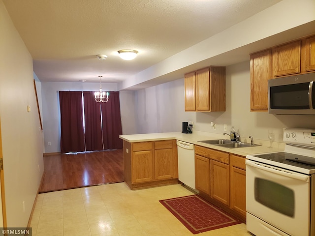 kitchen with sink, white appliances, an inviting chandelier, decorative light fixtures, and kitchen peninsula