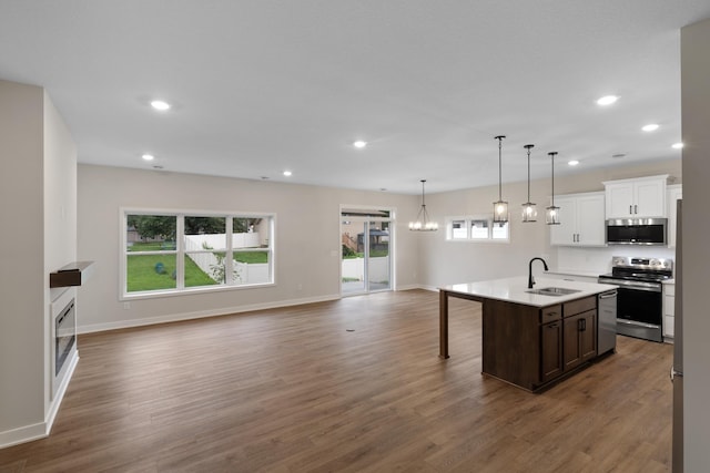 kitchen with a kitchen island with sink, sink, dark wood-type flooring, and appliances with stainless steel finishes