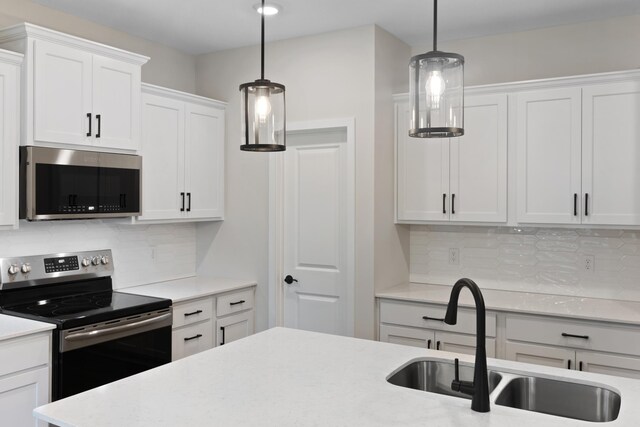 kitchen with decorative light fixtures, stainless steel appliances, white cabinetry, and sink