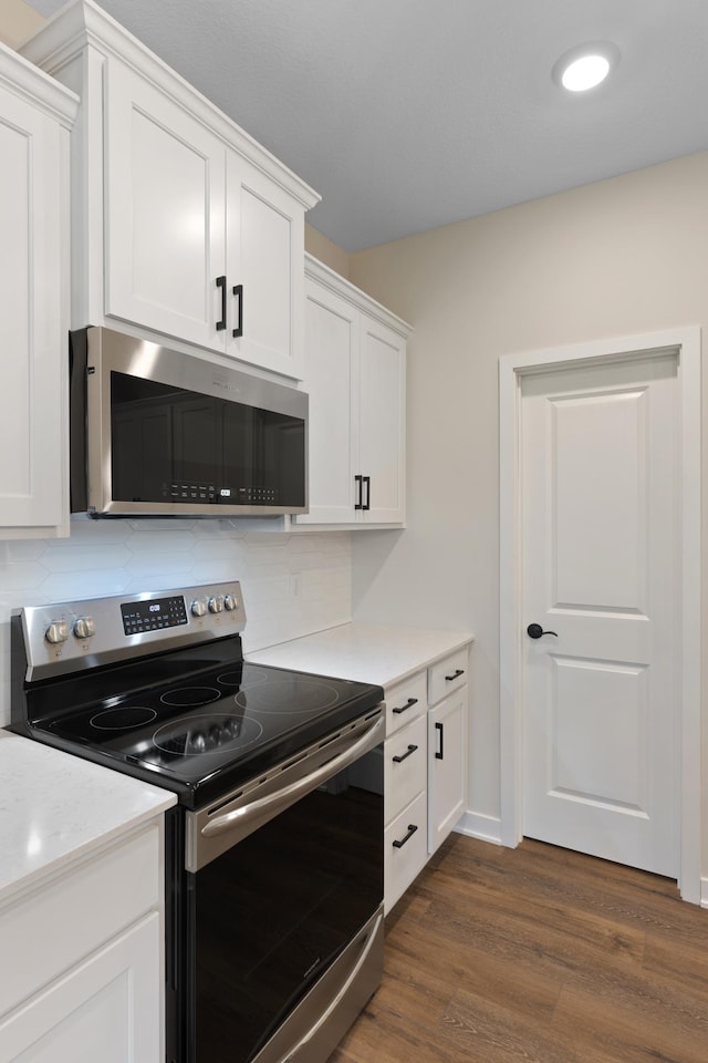 kitchen featuring appliances with stainless steel finishes, tasteful backsplash, white cabinetry, and dark wood-type flooring