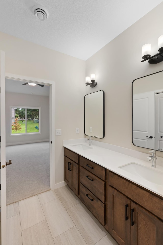 bathroom featuring ceiling fan, tile patterned flooring, vanity, and a textured ceiling