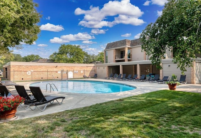 community pool with a lawn, a patio area, and fence