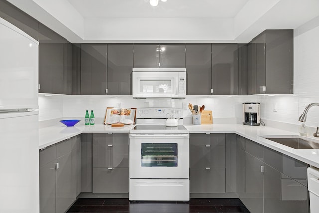 kitchen with white appliances, decorative backsplash, a sink, and gray cabinets