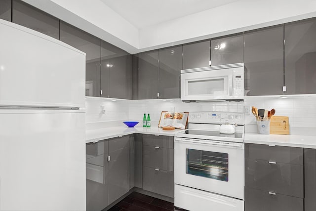 kitchen with dark wood finished floors, decorative backsplash, gray cabinetry, and white appliances