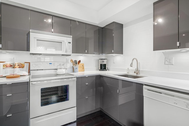kitchen with modern cabinets, a sink, white appliances, gray cabinets, and backsplash