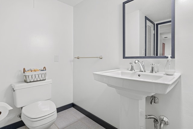 bathroom with toilet, a sink, and baseboards