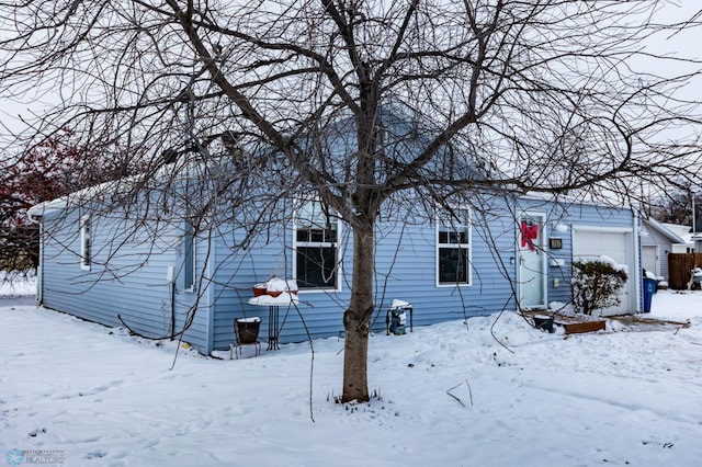 snow covered house featuring a garage