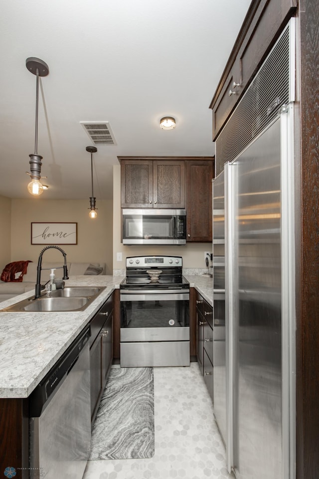 kitchen featuring sink, dark brown cabinetry, stainless steel appliances, and hanging light fixtures