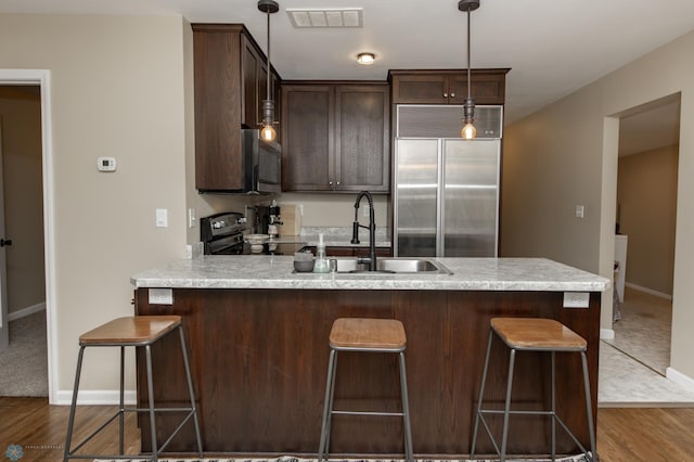 kitchen with pendant lighting, hardwood / wood-style floors, stainless steel appliances, and sink