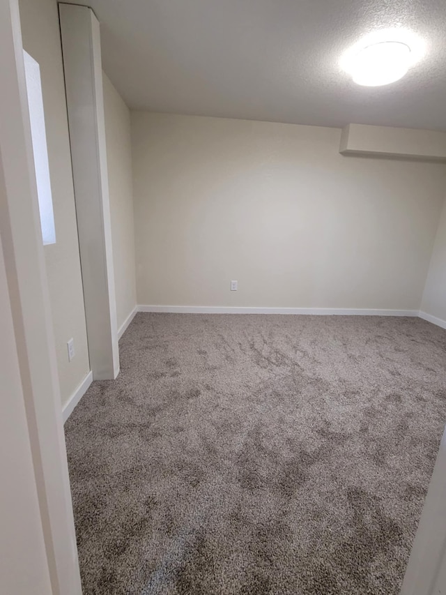 unfurnished room with carpet, a textured ceiling, and a wall mounted air conditioner