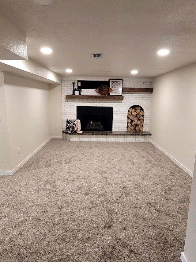 basement featuring a fireplace, a textured ceiling, and carpet floors