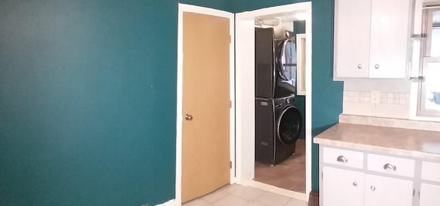 laundry room with stacked washer / dryer and light tile patterned floors