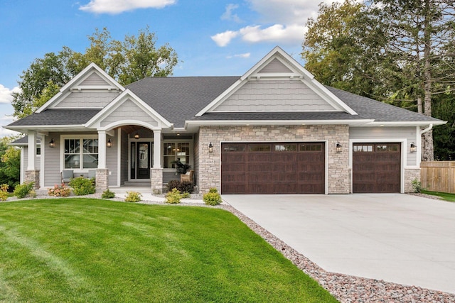 craftsman inspired home featuring a front lawn, concrete driveway, a garage, and roof with shingles