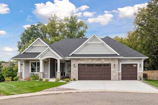 craftsman-style home with concrete driveway, stone siding, roof with shingles, an attached garage, and a front lawn