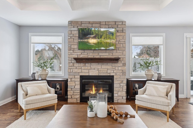 living area featuring coffered ceiling, a fireplace, baseboards, and wood finished floors