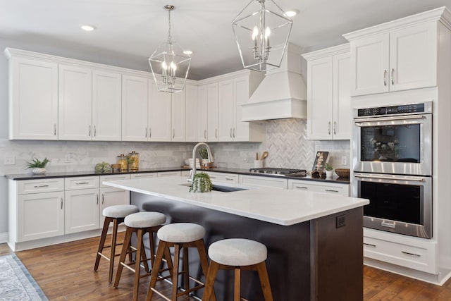 kitchen featuring stainless steel appliances, dark countertops, pendant lighting, and white cabinets