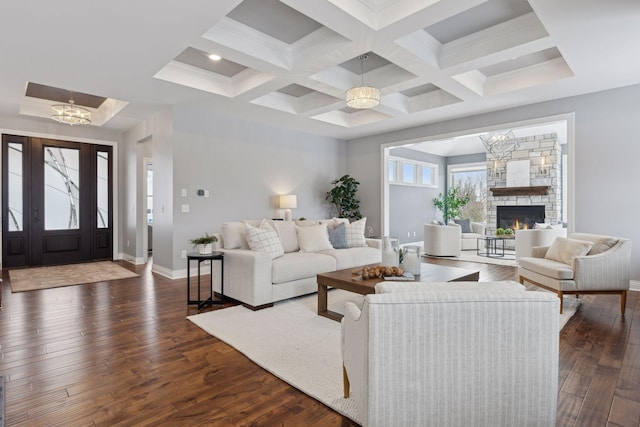 living area with a chandelier, a stone fireplace, baseboards, and dark wood-style floors