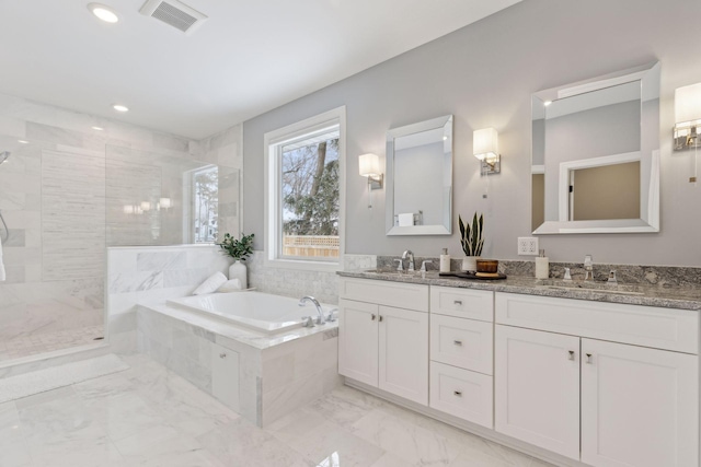 bathroom with marble finish floor, double vanity, visible vents, a sink, and a walk in shower