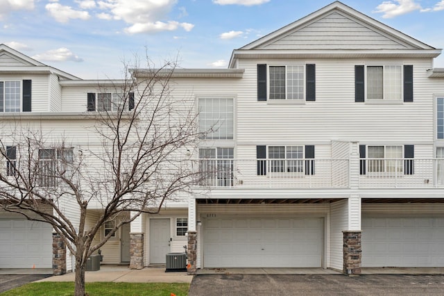 view of front of house featuring a balcony, central AC unit, and a garage