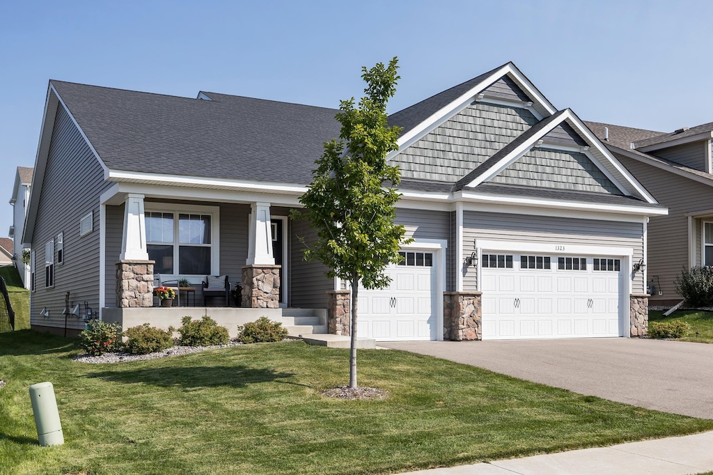 craftsman house with a porch, a garage, and a front lawn