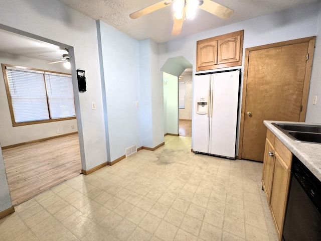 kitchen with a textured ceiling, stainless steel dishwasher, white refrigerator with ice dispenser, and light wood-type flooring