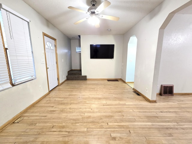 interior space with ceiling fan, a textured ceiling, and light wood-type flooring