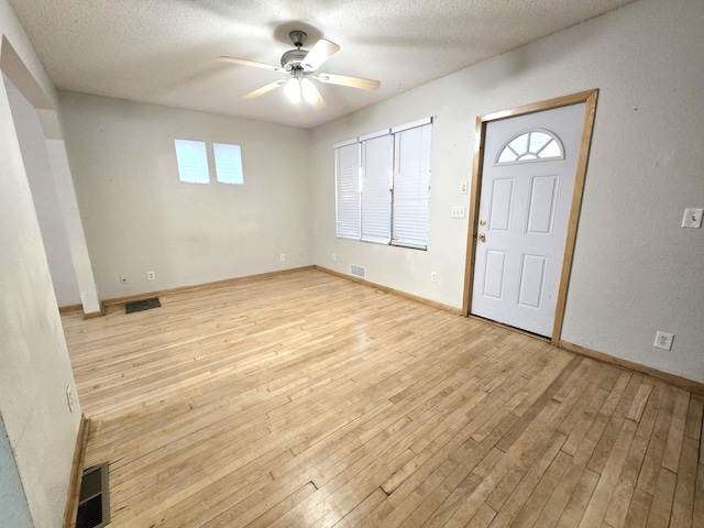 foyer entrance with a healthy amount of sunlight, a textured ceiling, and light wood-type flooring