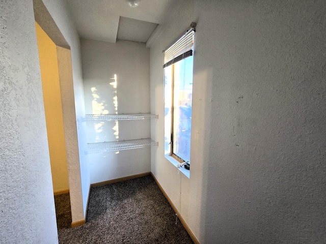 hallway featuring dark colored carpet and a textured ceiling