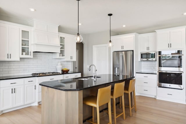 kitchen featuring tasteful backsplash, a center island with sink, decorative light fixtures, and appliances with stainless steel finishes