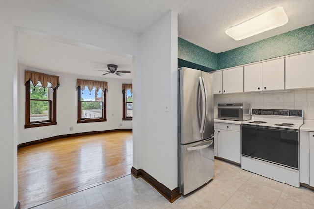 kitchen featuring baseboards, light countertops, appliances with stainless steel finishes, white cabinetry, and backsplash