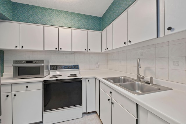 kitchen featuring electric range, white cabinetry, light countertops, and a sink