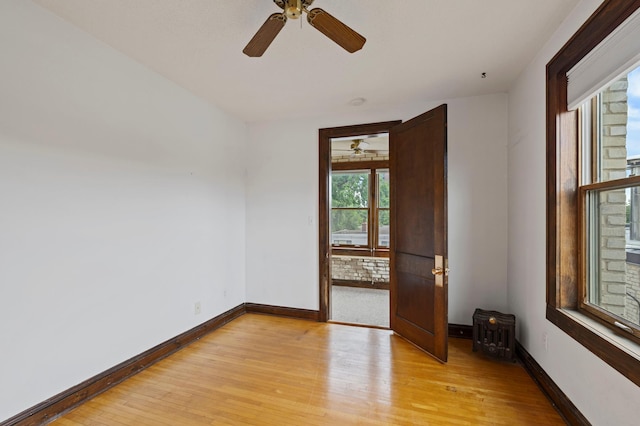 unfurnished room with baseboards, a ceiling fan, and light wood finished floors