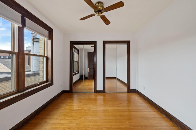 spare room featuring light wood-style flooring, a ceiling fan, and baseboards