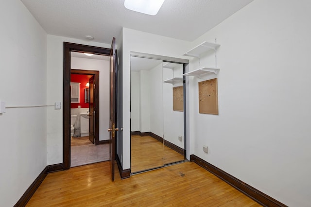 unfurnished bedroom with a closet, baseboards, and light wood finished floors