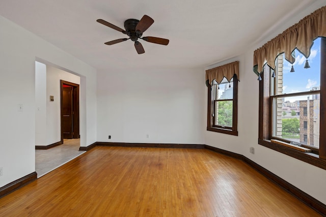 spare room featuring baseboards, wood-type flooring, and ceiling fan