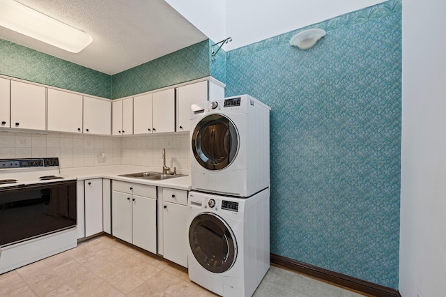 washroom with stacked washer and clothes dryer, a sink, a textured ceiling, wallpapered walls, and laundry area