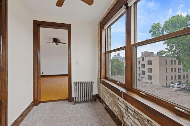 unfurnished sunroom featuring radiator heating unit and a ceiling fan