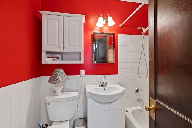 bathroom featuring vanity, tile walls, toilet, and shower / washtub combination