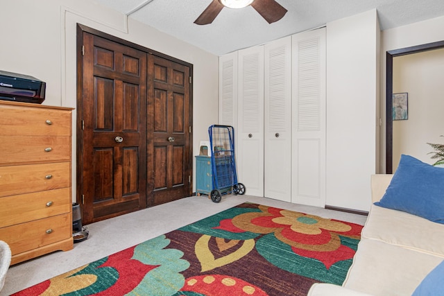 carpeted bedroom featuring ceiling fan and a textured ceiling