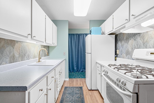 kitchen with white cabinetry, sink, backsplash, white appliances, and light hardwood / wood-style flooring