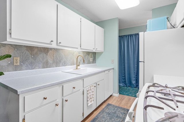 kitchen featuring white cabinetry, sink, and white appliances