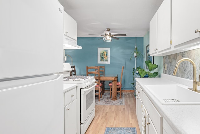 kitchen with sink, white cabinets, white appliances, light hardwood / wood-style floors, and exhaust hood